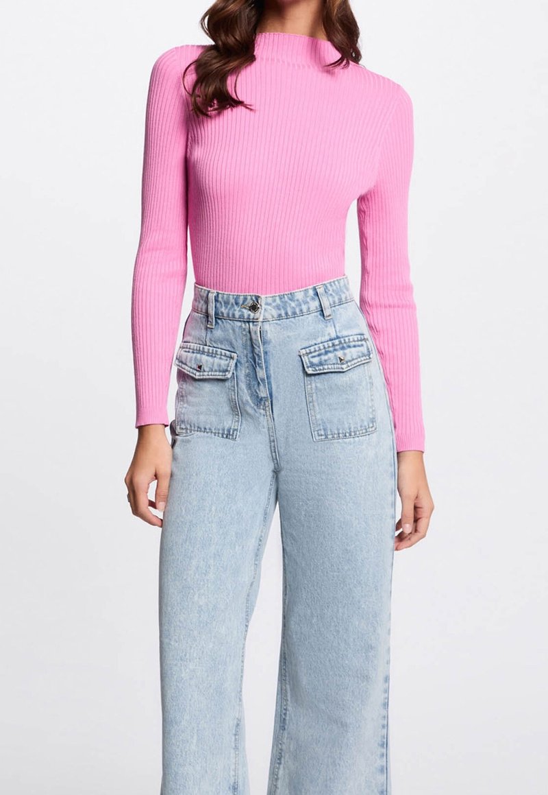 Top a manica lunga aderente a costine di un vivace rosa, abbinato a pantaloni ampi in denim azzurro a vita alta con tasche frontali.