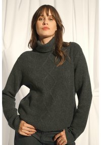 Szary, dziany sweter z golfem o prążkowanej fakturze i diamentowym wzorze z przodu. Posiada długie rękawy i luźny krój.