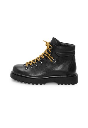 Musthave mustat nahast matkajalatsid paksu talla ja kollaste paeltega, mis on läbivalt metalli silmadega, kuvand külgvaates valgel taustal.