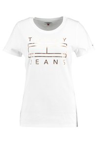 Vit bomulls t-shirt med korta ärmar, med en metallisk guld "TOMMY JEANS" logotyp på framsidan. Rund hals, avslappnad passform.