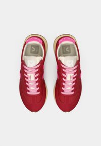 Κόκκινα και ροζ αθλητικά παπούτσια Veja με μπεζ σόλες και ροζ κορδόνια, σε οπτική από πάνω σε λευκό φόντο.