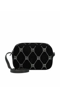 Bolso cruzado de ante negro con un patrón acolchado y tachuelas plateadas. Cuenta con una correa desmontable y cierre de cremallera. Forma rectangular compacta.