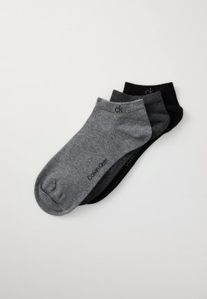 Tri par spodnjih nogavic v sivi in črni barvi, izdelanih iz elastičnega materiala z natisnjenimi logotipnimi detajli blizu zgornjega roba.