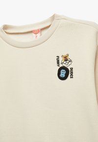 Sudadera beige con cuello de canalé, tigre bordado y texto "FUNNY DUDES" en negro y azul, con una textura suave y un diseño casual.