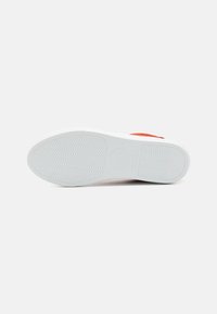 White rubber sneaker sole with textured grip pattern, featuring an orange upper accent. Smooth finish and rounded toe shape.
