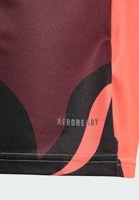 Camiseta deportiva AEROREADY con un tejido texturizado. Diseño de bloques de color en burdeos, negro y rosa con detalle de logo y costuras en contraste.