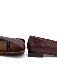 Ballerine in pelle bordeaux con un design a intaglio. Tacco quadrato nero e fodera interna color sabbia. Forma semplice e elegante con texture liscia.