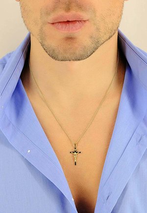 Collana con crocifisso in tono oro su una catena sottile, indossata sopra una camicia button-up azzurro chiaro. I dettagli notevoli includono un design a croce testurizzato.