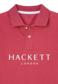 Rotes Polo-Shirt mit zwei weißen Knöpfen und "HACKETT LONDON" in Weiß auf der Vorderseite unter dem Kragen aufgedruckt.