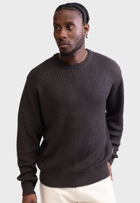 Mørkebrun strikket sweater med en geometrisk tekstur, rund halsudskæring og ribbede manchetter, designet i en afslappet pasform.