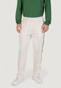 Sportliche Hosen in Creme mit strukturiertem Finish, elastischem Bund, seitlichen Streifen in Dunkelgrün und einem lockeren Schnitt.