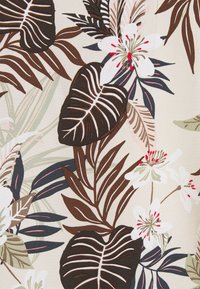 Tessuto floreale con grandi foglie verde scuro e marrone, fiori bianco sporco e dettagli rosa delicato su uno sfondo beige chiaro.