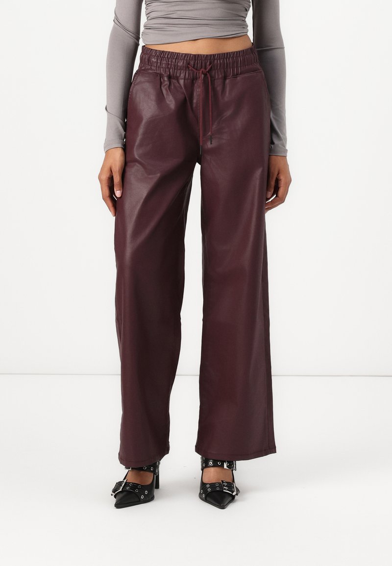 Burgundske široke hlače iz umetnega usnja z elastiko in vrvico. Gladka tekstura z sijočim zaključkom.