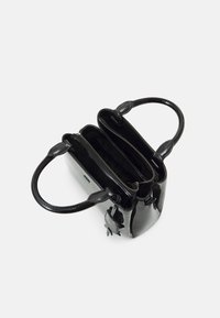 Svart glansig handväska med två handtag, dragkedjestängning och flera inre fack. Har en liten dekorativ accent på sidan.