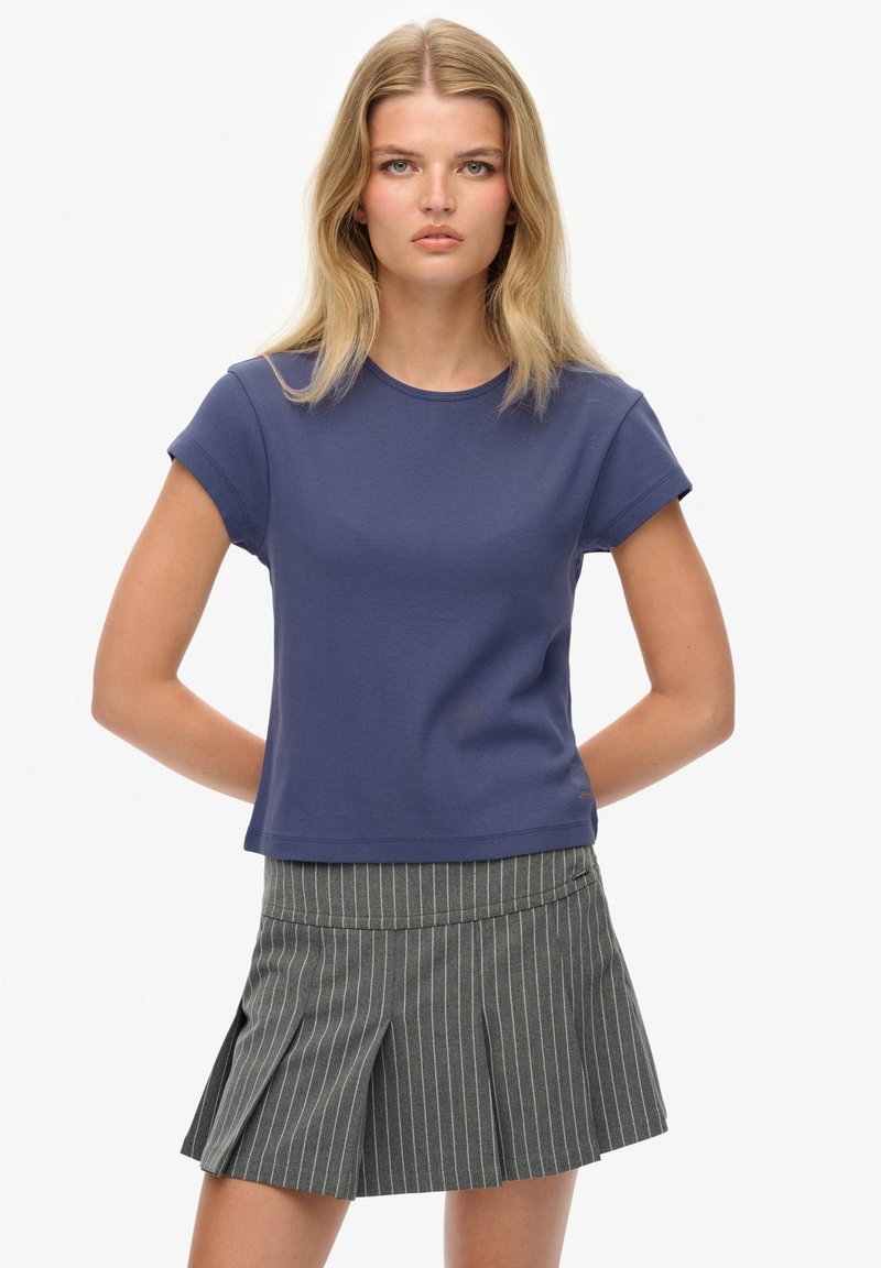 Camiseta de manga corta azul marino con cuello redondo, combinada con una falda plisada a rayas grises. Mezcla de algodón, textura suave.