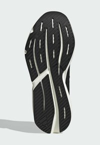 Podošok so textúrovaným čiernym gumovým povrchom s vzorom dezénu. Biele akcenty pozdĺž okrajov a drážky pre trakciu.