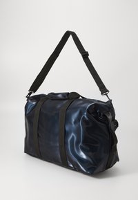 Una borsa da ginnastica di un blu scuro e lucido con due manici neri robusti, posizionata su uno sfondo neutro.