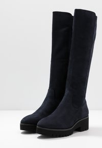 Bottes hauteur genou en daim bleu foncé, avec une texture lisse, un bout arrondi et un talon épais doté d'une semelle rainurée pour une meilleure adhérence.