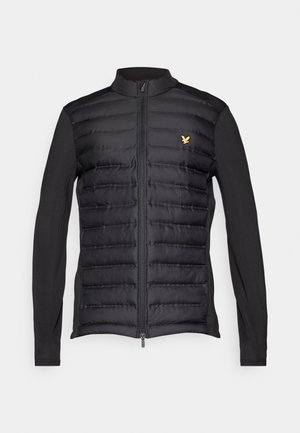 Schwarze Puffjacke mit Reißverschluss vorne, die ein tailliertes Design und weiche Stoffärmel hat. Goldenes Logo-Detail auf der linken Brust.