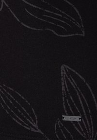 Tissu noir présentant un motif de feuilles subtil dans une teinte plus foncée, avec une étiquette métallique LASCANA attachée. Texture douce, vue en gros plan.