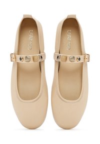 Zapatos planos beige con puntera redonda, parte superior de material sintético liso, correa ajustable y acentos decorativos de metal.