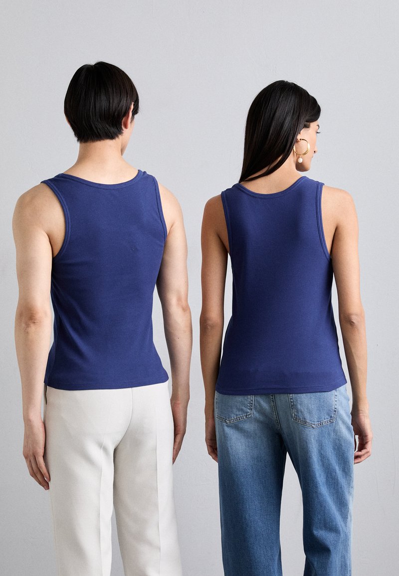 Marineblaue ärmellose Tops, getragen von zwei Personen. Der Stoff wirkt weich, hat ein tailliertes Design und einen dezenten runden Ausschnitt.