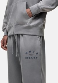 Gray cotton blend hoodie and sweatpants, featuring a front pocket, ribbed cuffs, and "GOOD for NOTHING" print in navy on pants.