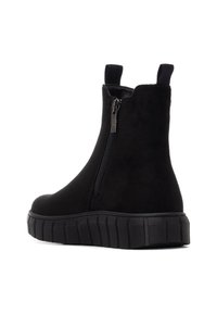 Botines de ante negros con cremallera lateral, tiradores elásticos y suela gruesa texturizada para agarre y soporte.
