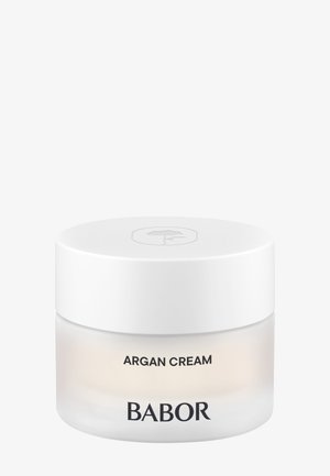 Witte ronde pot met een gladde afwerking; doorzichtig glazen bodem; gelabeld "ARGAN CRÈME" en "BABOR" in zwarte tekst; minimalistisch ontwerp.