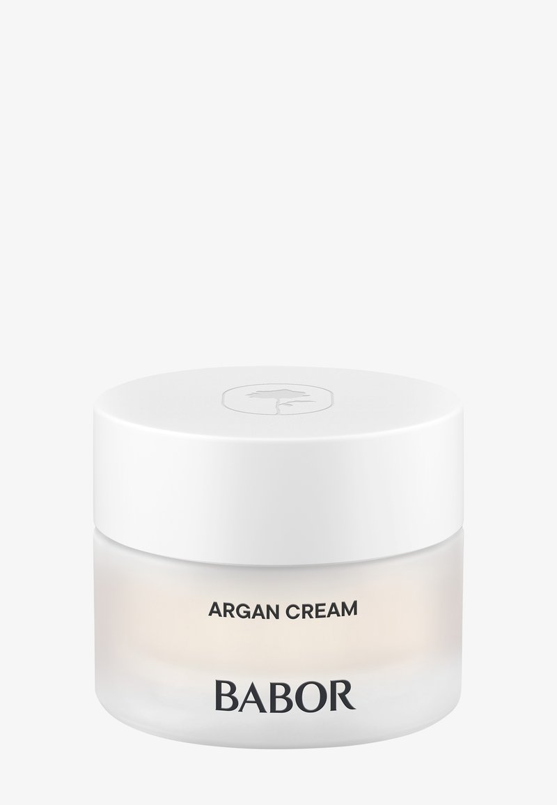 Vit rund burk med en slät yta; klar glasbotten; märkt "ARGANCREME" och "BABOR" i svart text; minimalistisk design.