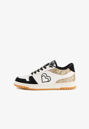 Baskets blanches avec des accents en daim noir et un détail en paillettes dorées au talon. Présente un bout perforé et un logo cœur noir sur le côté.