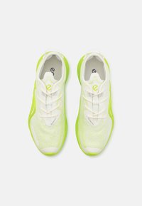 Fehér és neon zöld sportcipők légáteresztő hálós felsőrésszel, texturált mintázattal, részletes fűzőkkel és párnázott talppal.