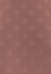Textured fabric in dusty rose color featuring a raised dot pattern on a grid-like background, creating a tactile and visual contrast.