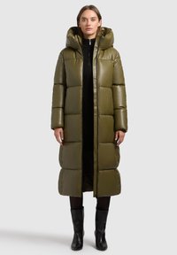 Lange olijfgroene pufferjas met een capuchon, voorzien van een gewatteerd ontwerp, een gladde textuur en een ritssluiting aan de voorkant.