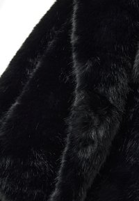 Tessuto in pelliccia sintetica nera con una consistenza densa e morbida, che mostra fibre di varie lunghezze e una superficie liscia e lucida. Nessun motivo o accento visibile.