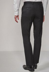 Pantaloni negri formali cu o croială dreaptă, cu două buzunare la spate cu nasturi și un material neted, texturat. Purtați cu pantofi negri.