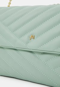 Gep quiltete mintgrüne Kunstledertasche mit goldfarbenen Beschlägen und diagonaler Naht. Sie verfügt über ein kleines geprägtes Logo auf der Vorderseite.