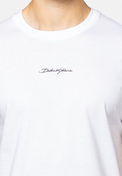 Witte katoen t-shirt met een ronde hals, voorzien van een zwart cursief logo "Dolce&Gabbana" op de borst. Zacht materiaal en getailleerd ontwerp.