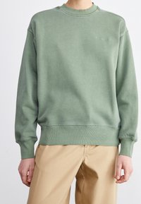Felpa crewneck verde realizzata in cotone, con polsini e orlo a coste, e con un branding sottile sul petto in filo abbinato.