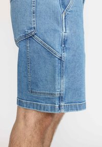 Lichte blauwe denim shorts met een rechte snit, contrasterende stiksels, zijzakken en een omgeslagen zoom op knielengte.