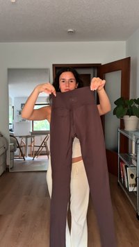 Mørkebrune, højtaljede leggings lavet af strækbart materiale, med en glat tekstur og baglommer.