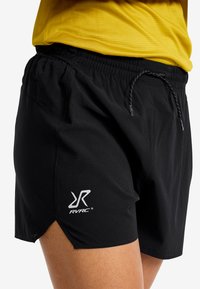 Svarta idrottsshorts med elastisk midja, dragsko och logotyp. Texturerat tyg med sidoflikar för rörelsefrihet.