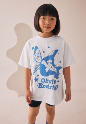 Hvid bomuld T-shirt med blåt motiv, der viser en siddende figur med sommerfuglevinger, ledsaget af stjerner og teksten "Olivia Rodrigo."