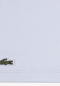 Γαλάζια βαμβακερή μπλούζα με ριμπ υφή, με μικρό πράσινο λογότυπο κροκόδειλου κεντημένο στην κάτω αριστερή γωνία.