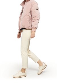 Ljusrosa puffjacka med diamantstitching, krämfärgade cropped byxor och vita sneakers med bruna souldetaljer. Enkelt, sportigt design.