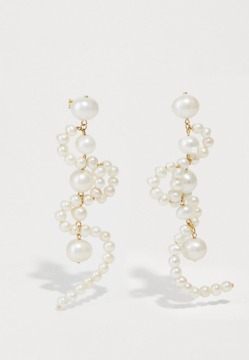 Λευκά περιδέραια με μαργαρίτες σε σπειροειδές σχέδιο, με διάφορα μεγέθη μαργαριταριών και χρυσές λεπτομέρειες. Λείος υφή και κομψό σχήμα.