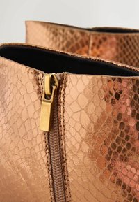 Bottines en bronze, motif serpent texturé, avec une fermeture éclair dotée de quincaillerie dorée et une doublure intérieure noire.