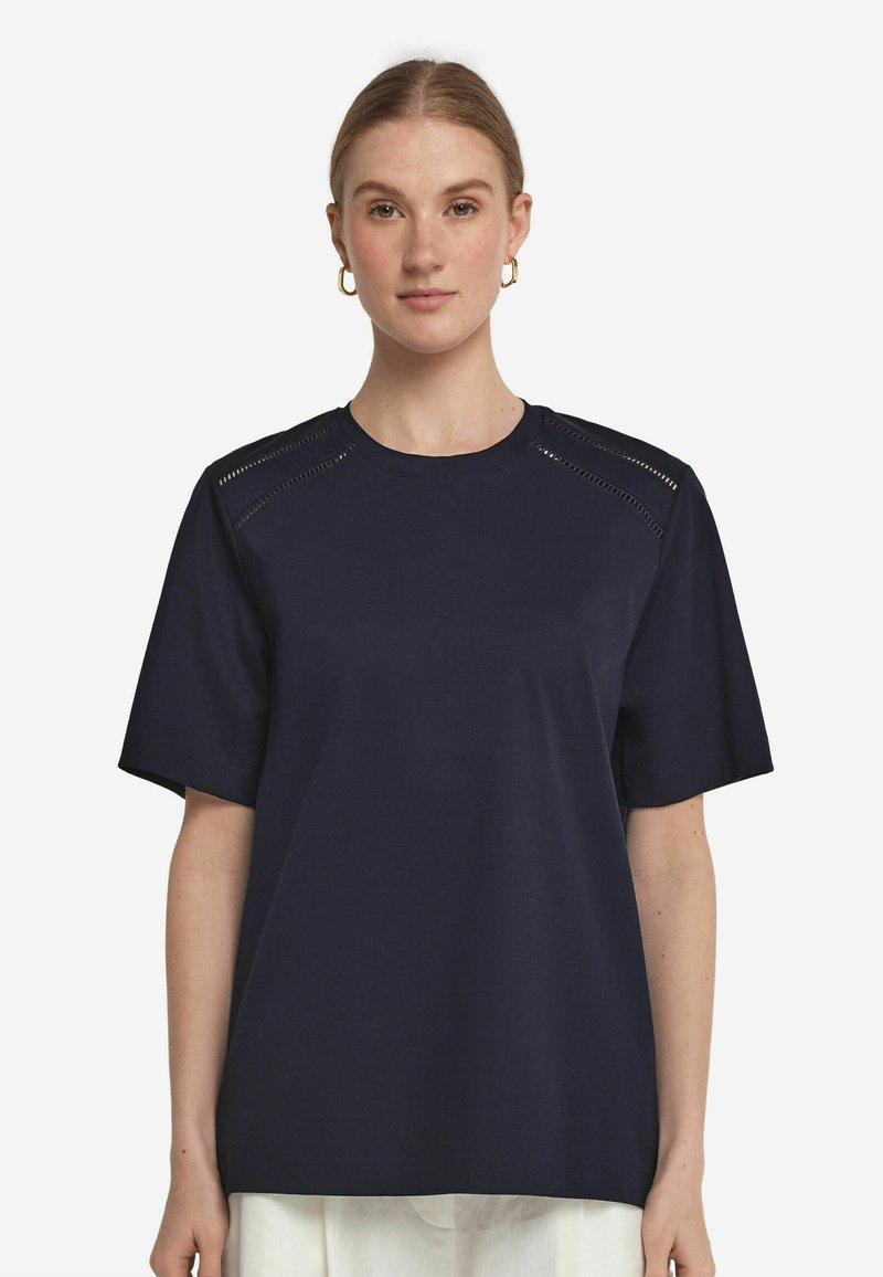 Mörkblå kortärmad t-shirt i mjukt tyg, med utskärningar på axelsömmarna, avslappnad passform och rundad halsringning.