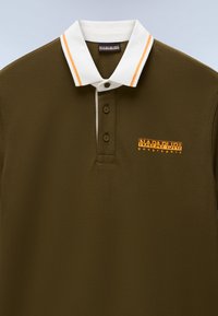 Πράσινο χακί πόλο πουκάμισο με λευκό γιακά που έχει πορτοκαλί ρίγες και πορτοκαλί λογότυπο "Napapijri geographic" στο αριστερό στήθος.