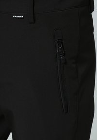 Pantalones softshell negros con un bolsillo lateral con cremallera y una textura suave. La cinturilla está equipada con una etiqueta de marca discreta.
